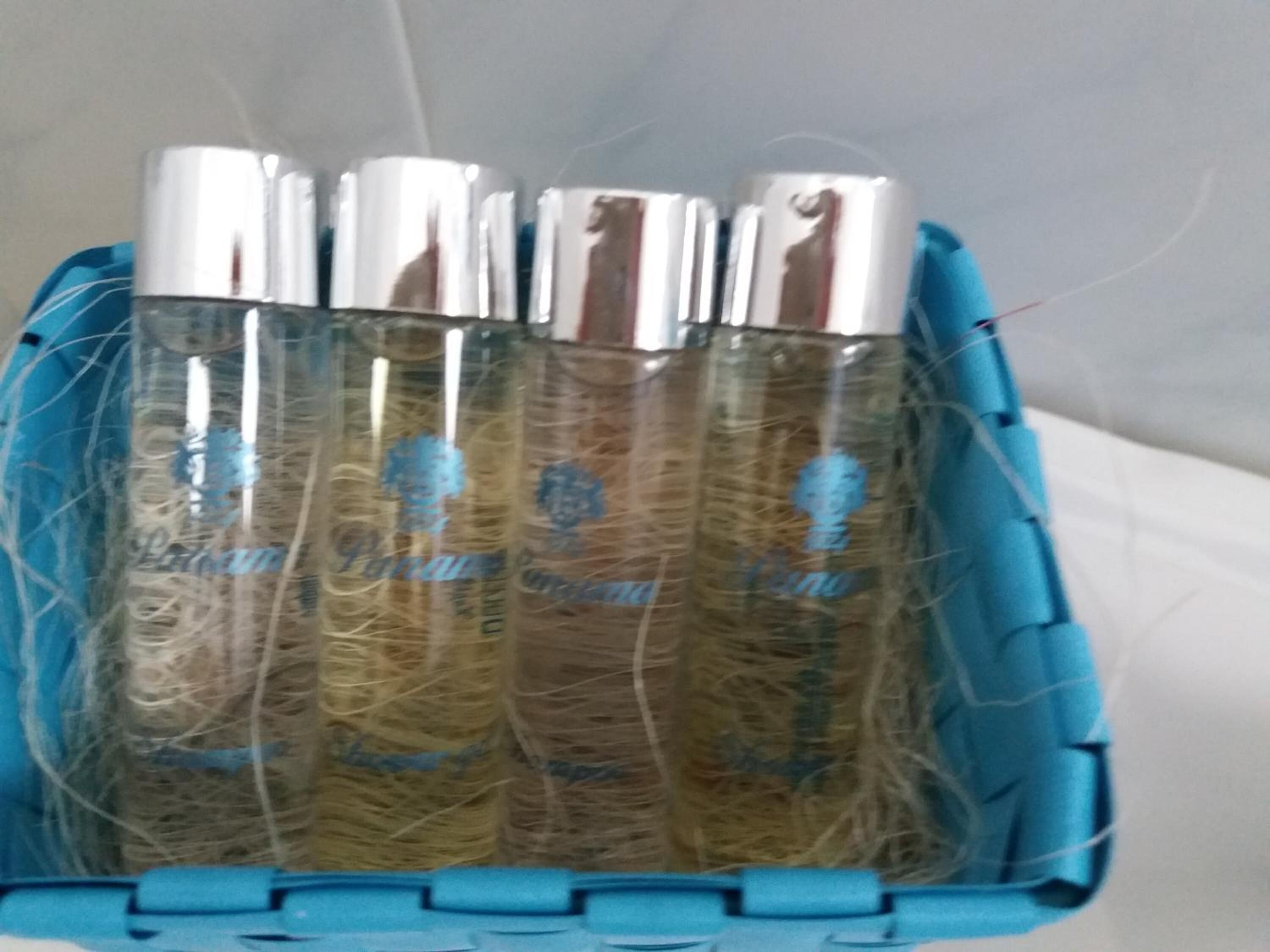 A basket containing three bottles of liquid with a straw, placed on a surface.