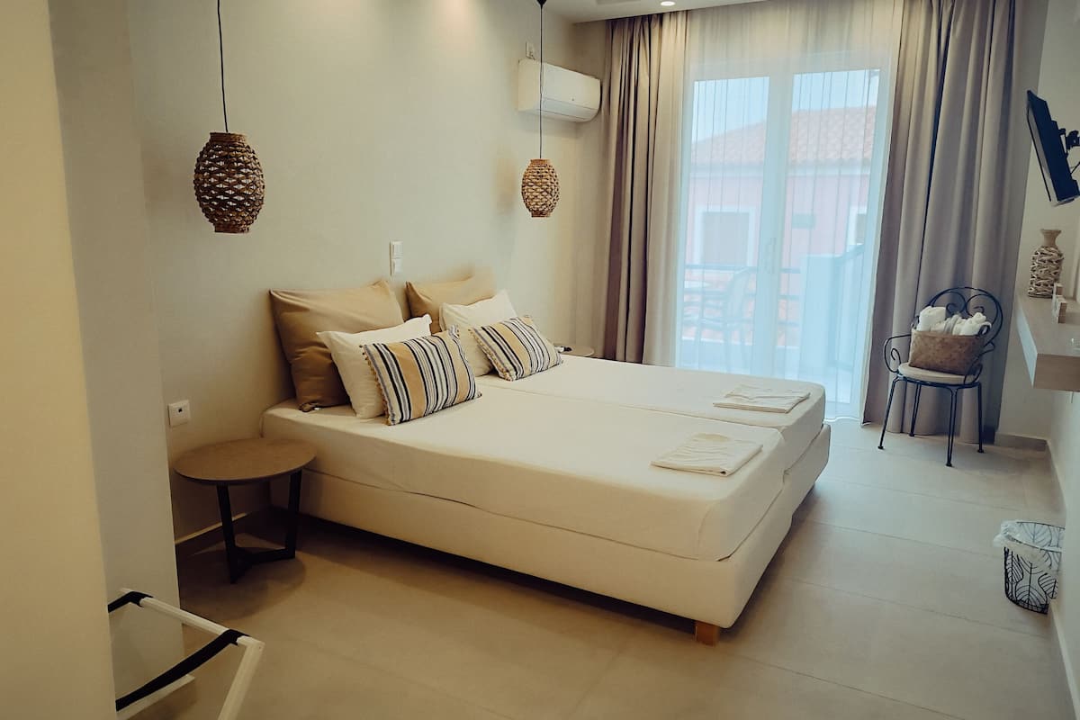 Un dormitorio moderno con una cama grande, mesitas de noche, una silla y un ventanal con cortinas.