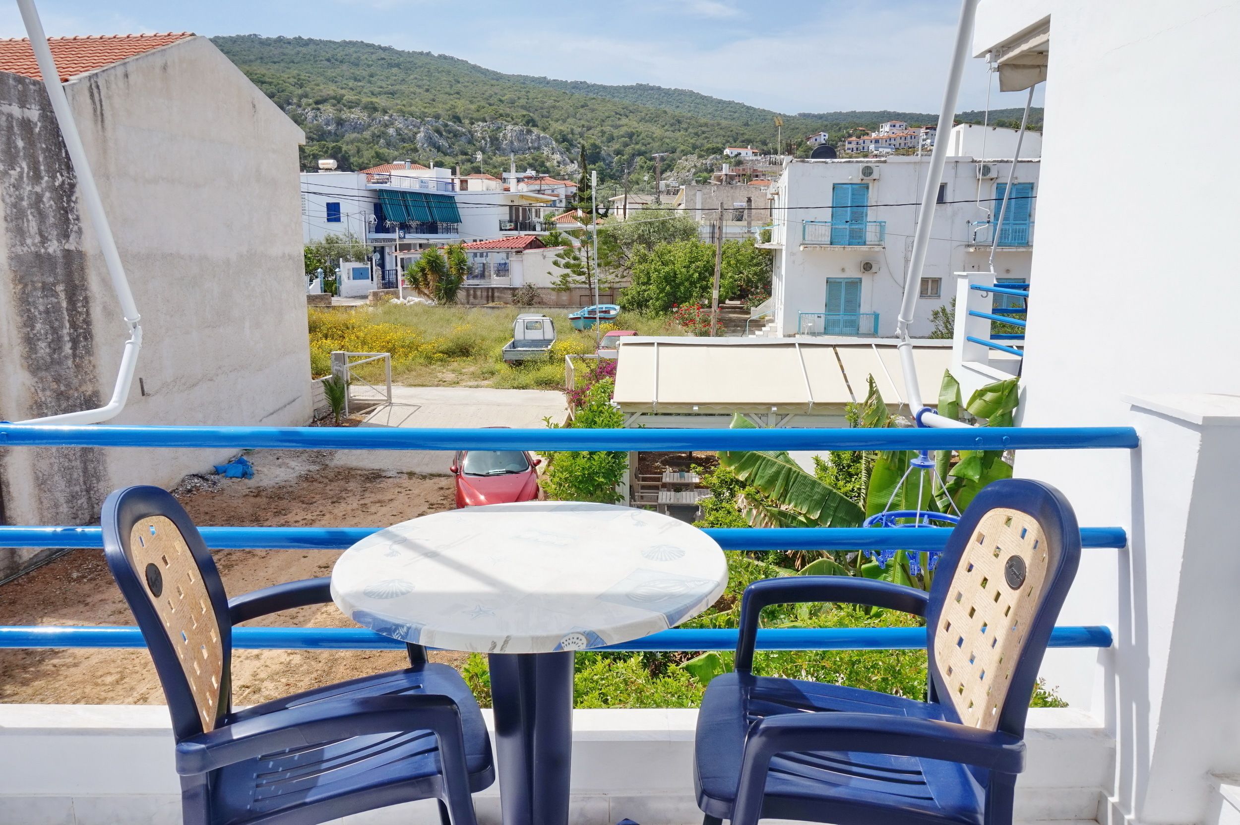 A balcony with blue railings, two chairs, and a small round table.