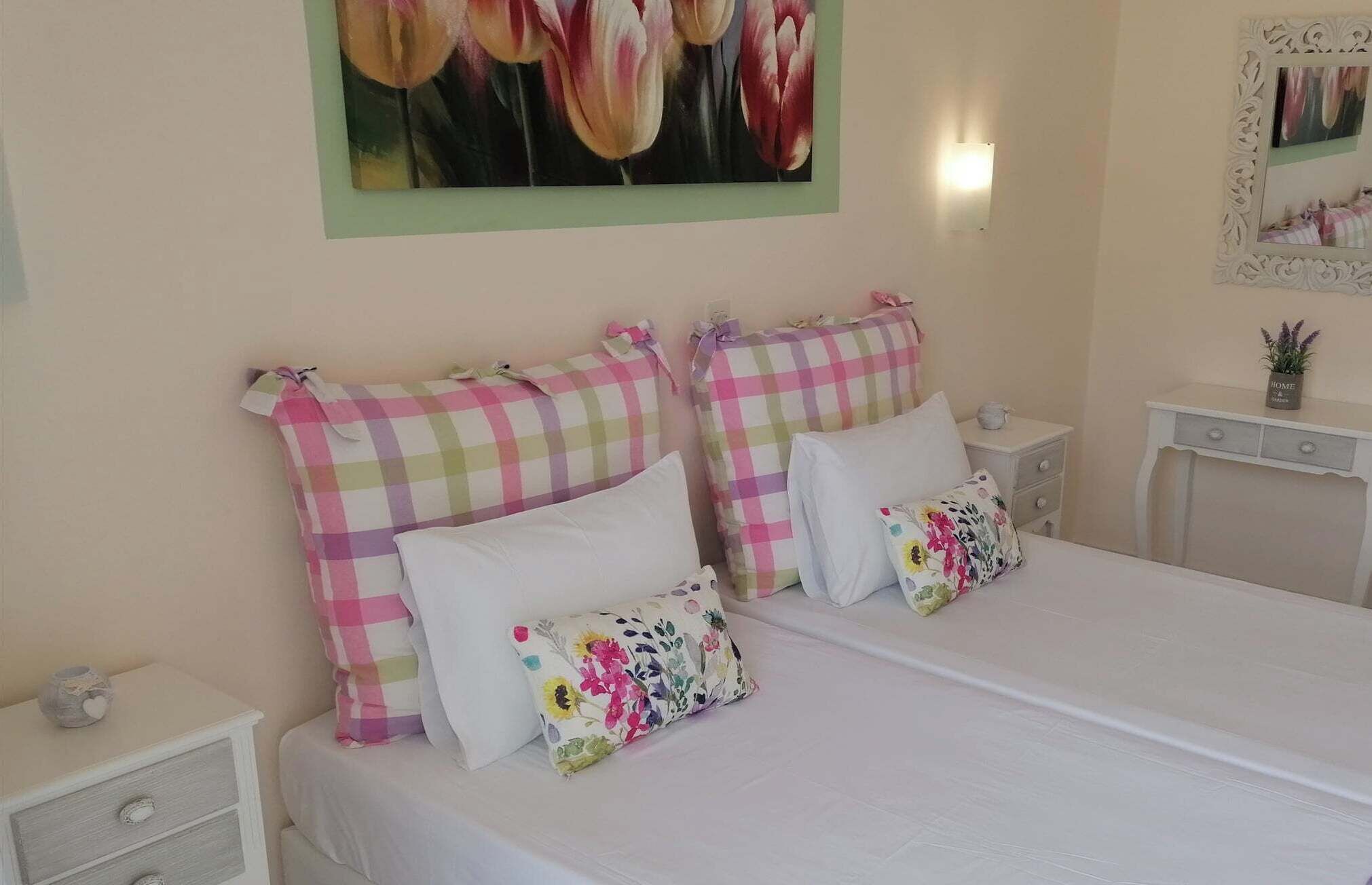 A bedroom with a large bed, two nightstands, a wall-mounted light, and a framed picture above the bed.
