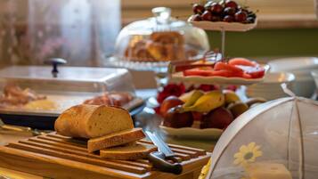 A breakfast buffet with bread, fruits, and a variety of pastries.