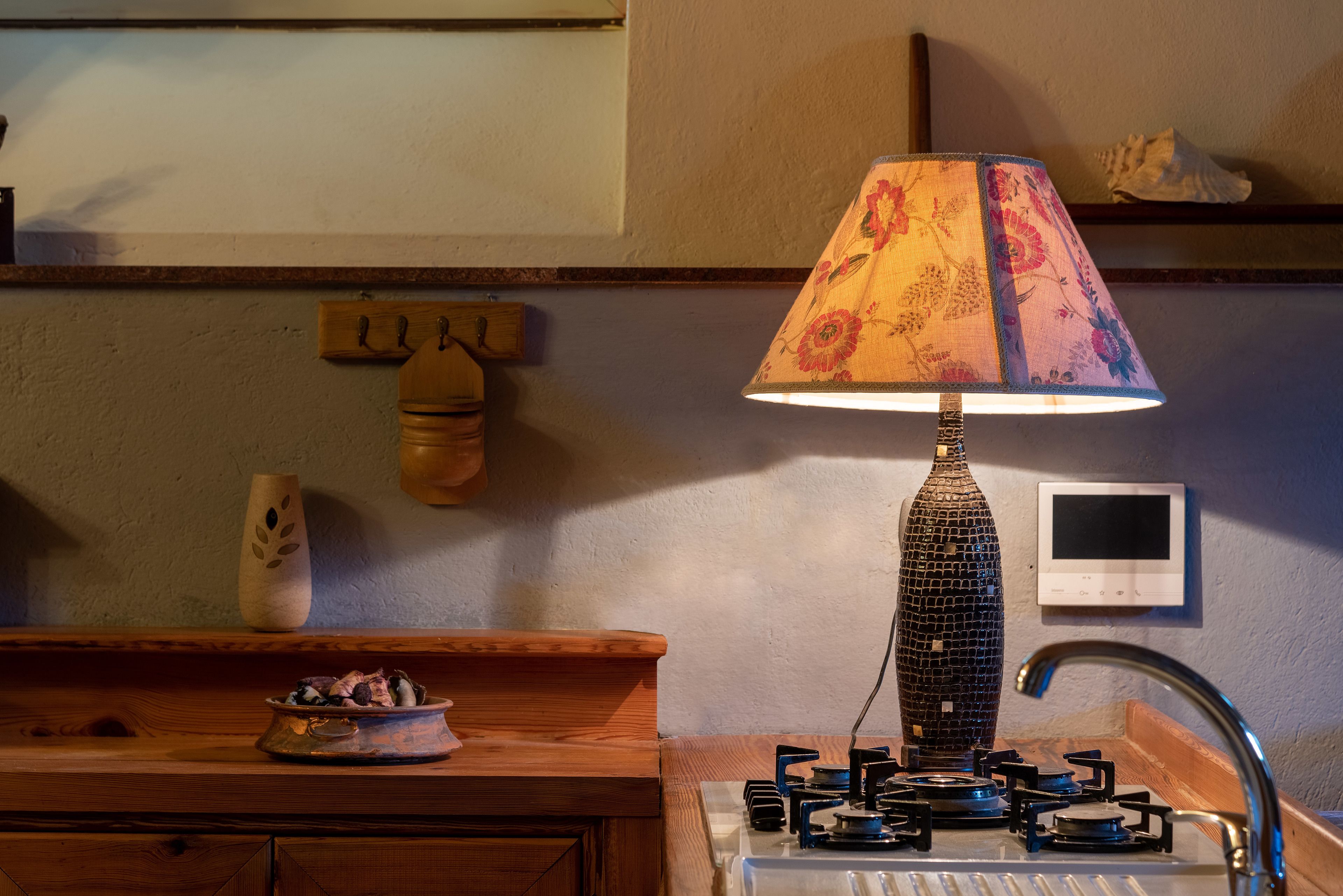 A kitchen with a wooden countertop, a decorative lamp, a stove, and a wall-mounted thermostat.