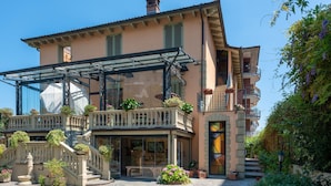 A multi-story building with a glass conservatory, stone steps, and outdoor seating. - Villa Mery (Casale Monferrato)