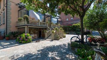 A courtyard with stone flooring, a staircase, potted plants, and a bicycle.