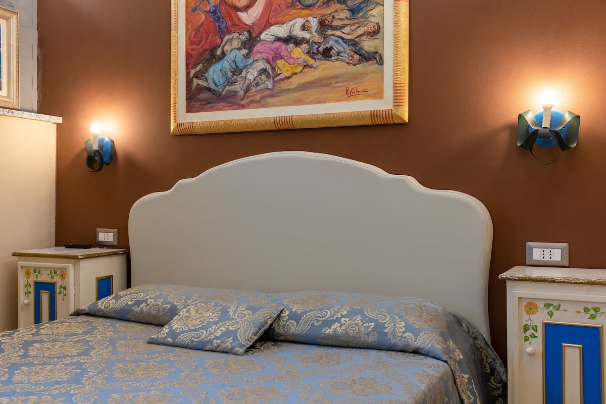 Une chambre à coucher avec un lit, des tables de chevet et un tableau accroché au mur.
