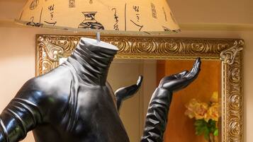 Una estatua de una figura con los brazos extendidos y una superficie reflectante frente a un espejo ornamentado con un marco decorativo.