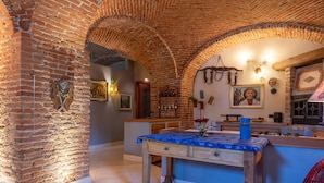 A rustic kitchen with exposed brick walls, a wooden table, and a brick oven. - Villa Mery (Casale Monferrato)
