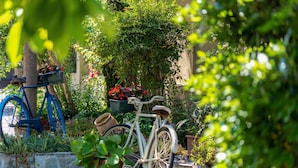 A bicycle parked in a garden with potted plants and flowers. - Villa Mery (Casale Monferrato)
