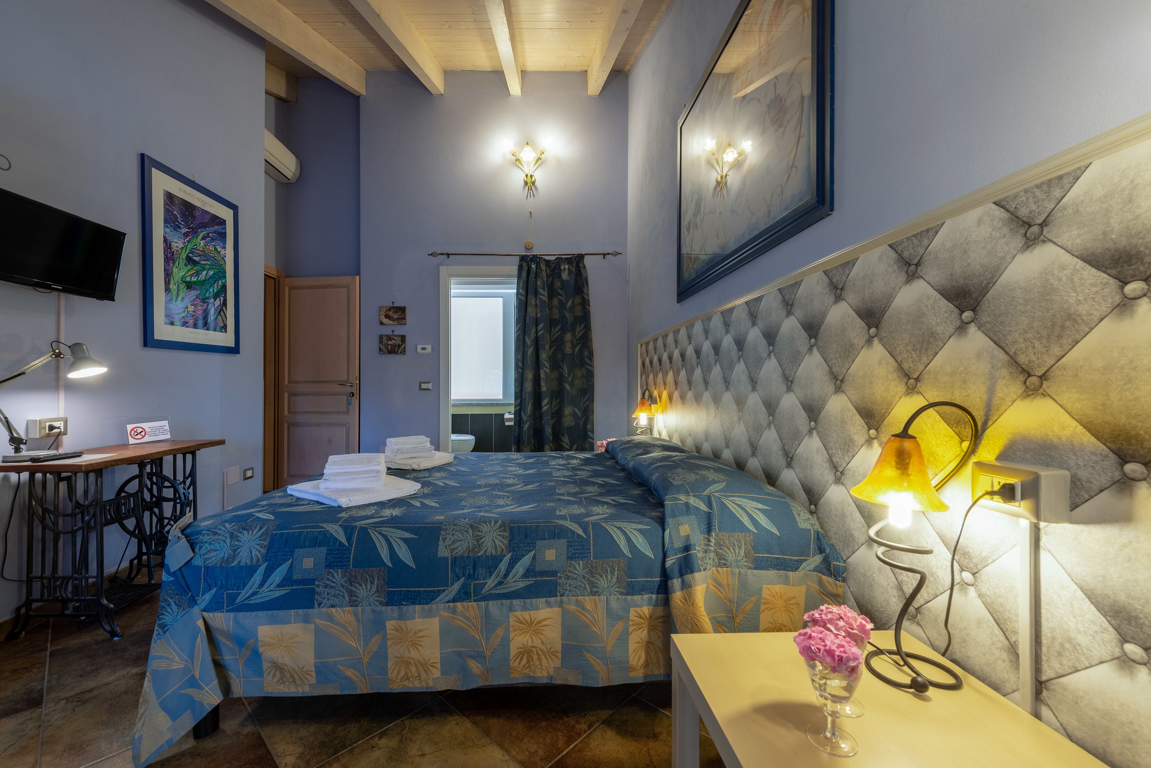 Une chambre à coucher avec un lit, un bureau, une chaise, une télévision et une lampe.