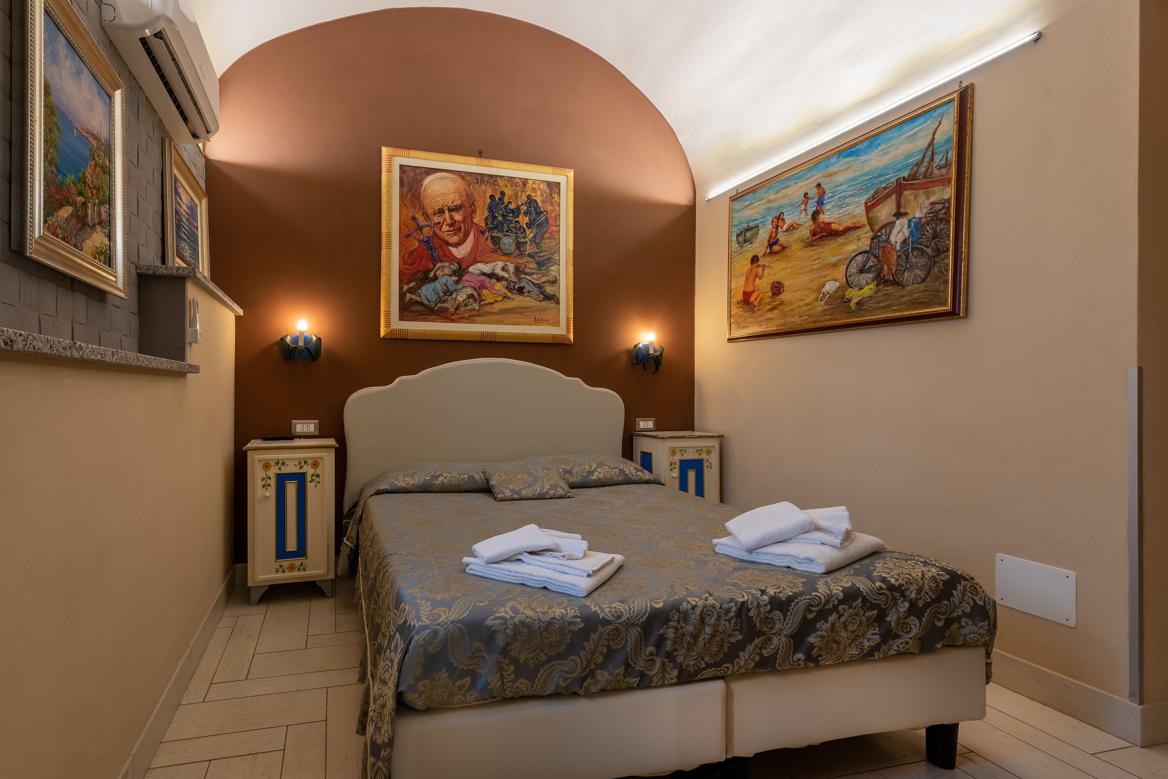 Una camera d'albergo con un letto grande, due comodini e due lampade a parete.