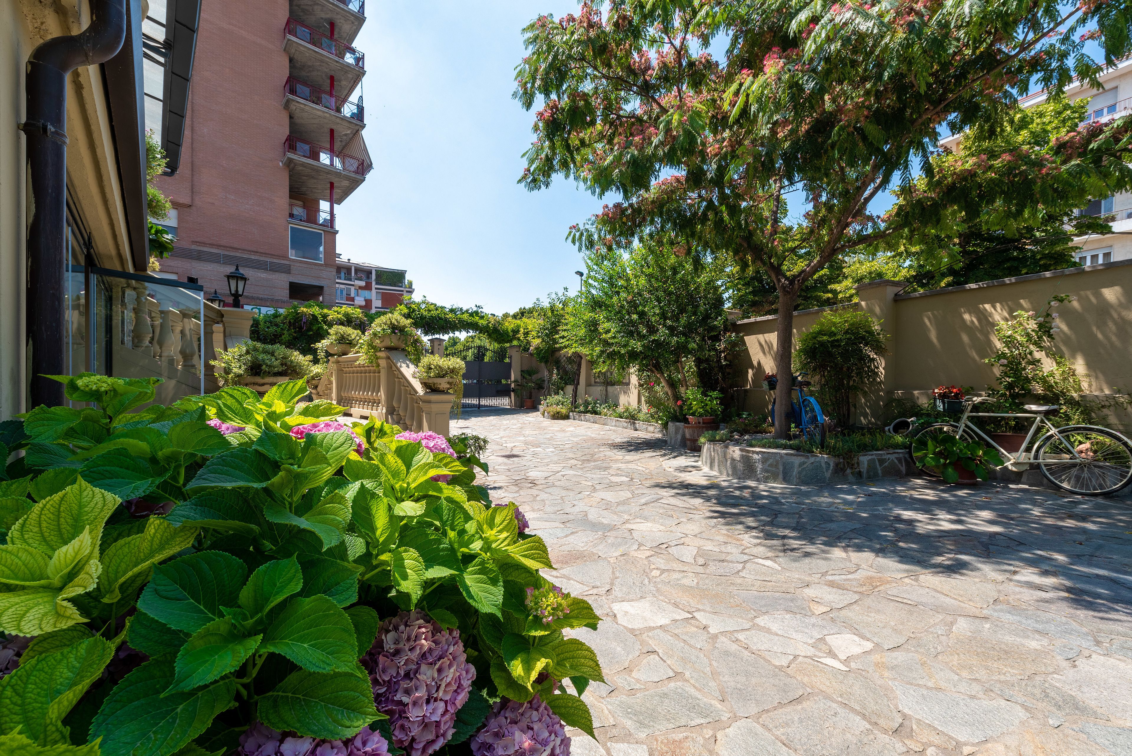 Une cour pavée de pierres, avec un vélo, des plantes en pot et un bâtiment doté de balcons.