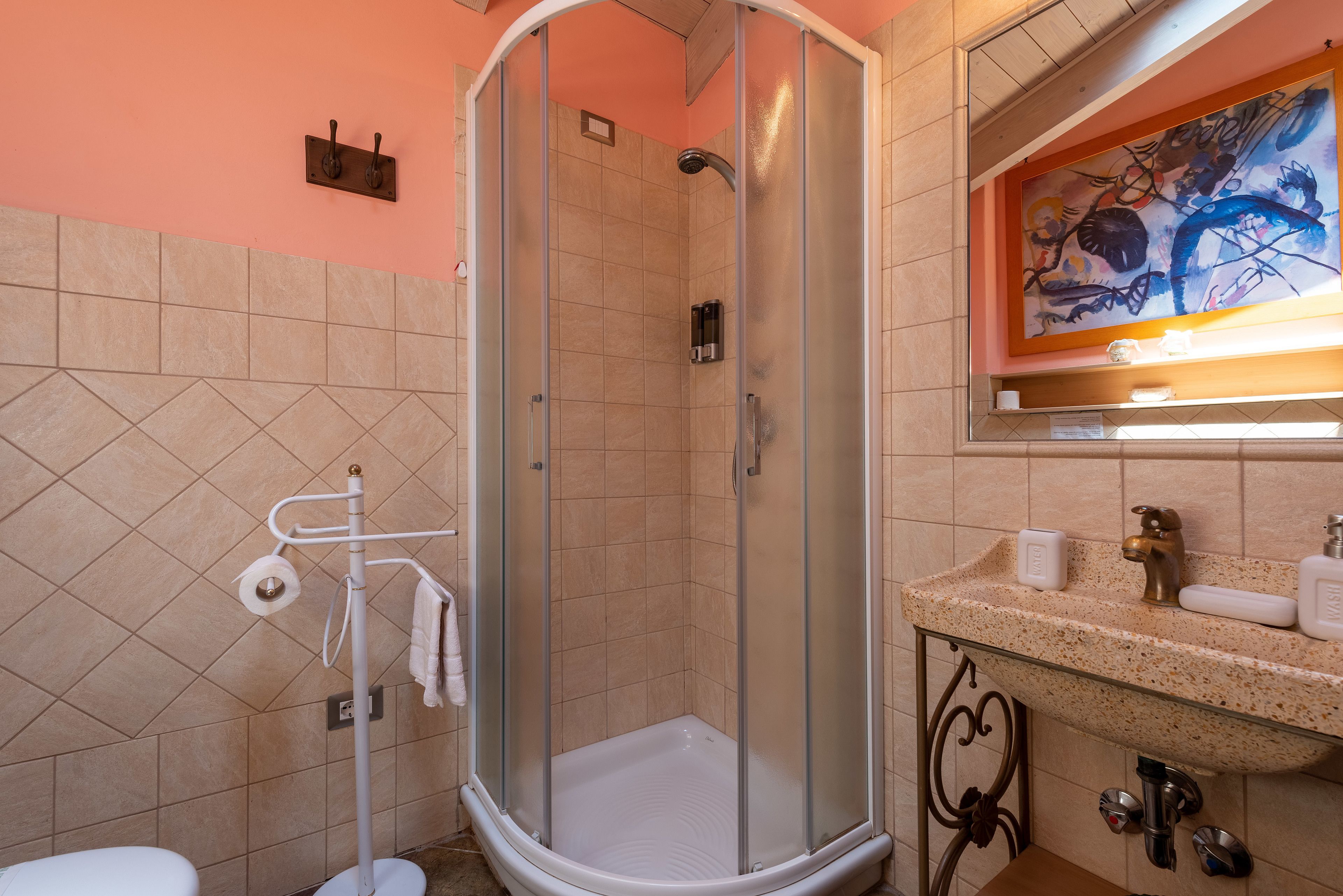 A bathroom with a glass-enclosed shower, a sink with a marble countertop, and a wall-mounted towel rack.