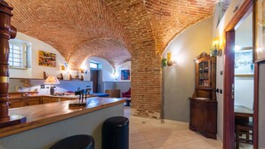 A spacious kitchen with a brick ceiling, wooden bar counter, and modern appliances. - Villa Mery (Casale Monferrato)