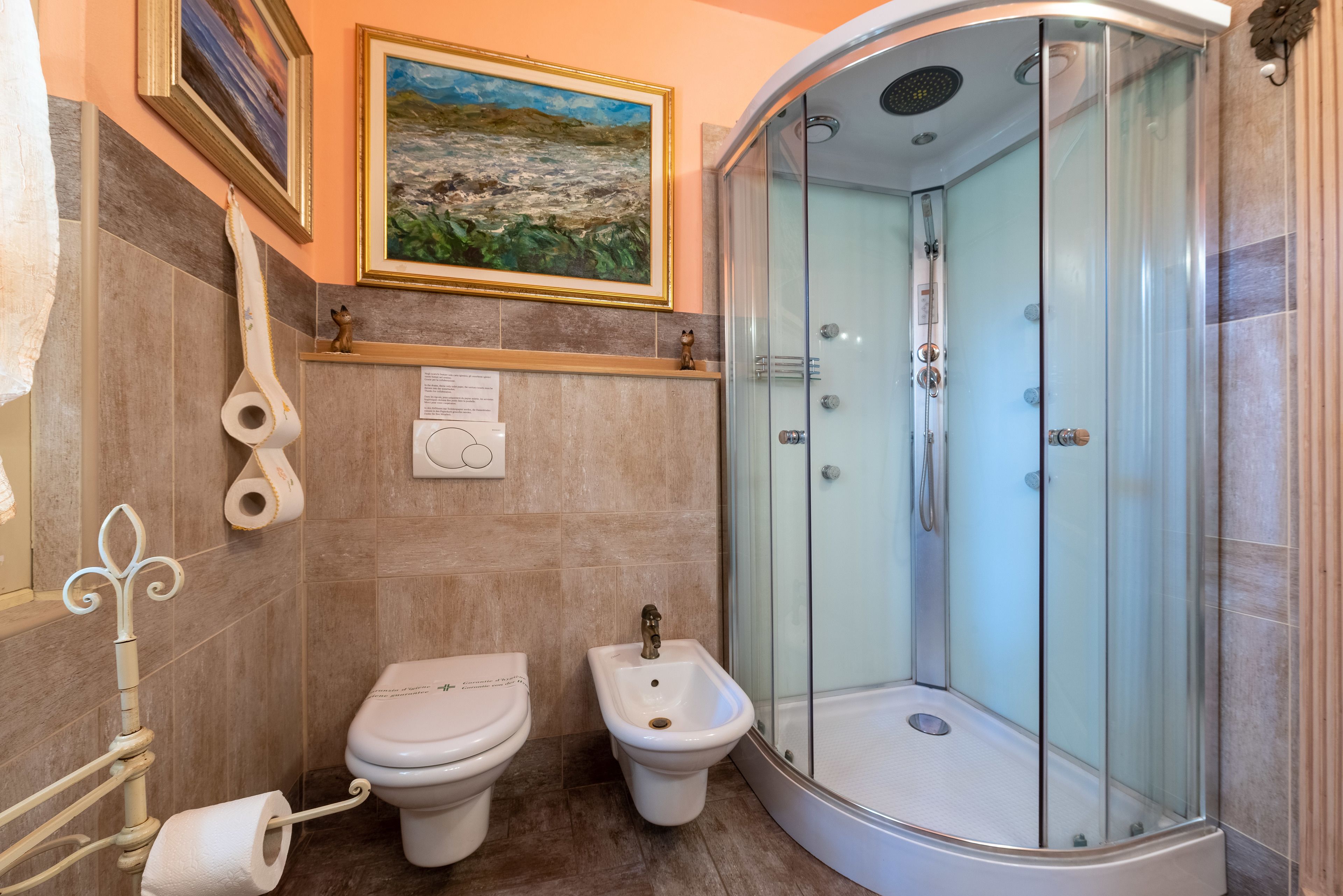 Une salle de bain équipée de toilettes, d’un bidet et d’une douche à parois de verre.