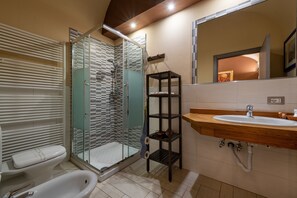 Une salle de bain moderne dotée d’une douche à parois de verre, de toilettes blanches, d’une baignoire sur pieds et d’un meuble-lavabo en bois avec un évier.