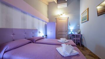 A hotel room with two beds, a desk, a chair, and a wardrobe.