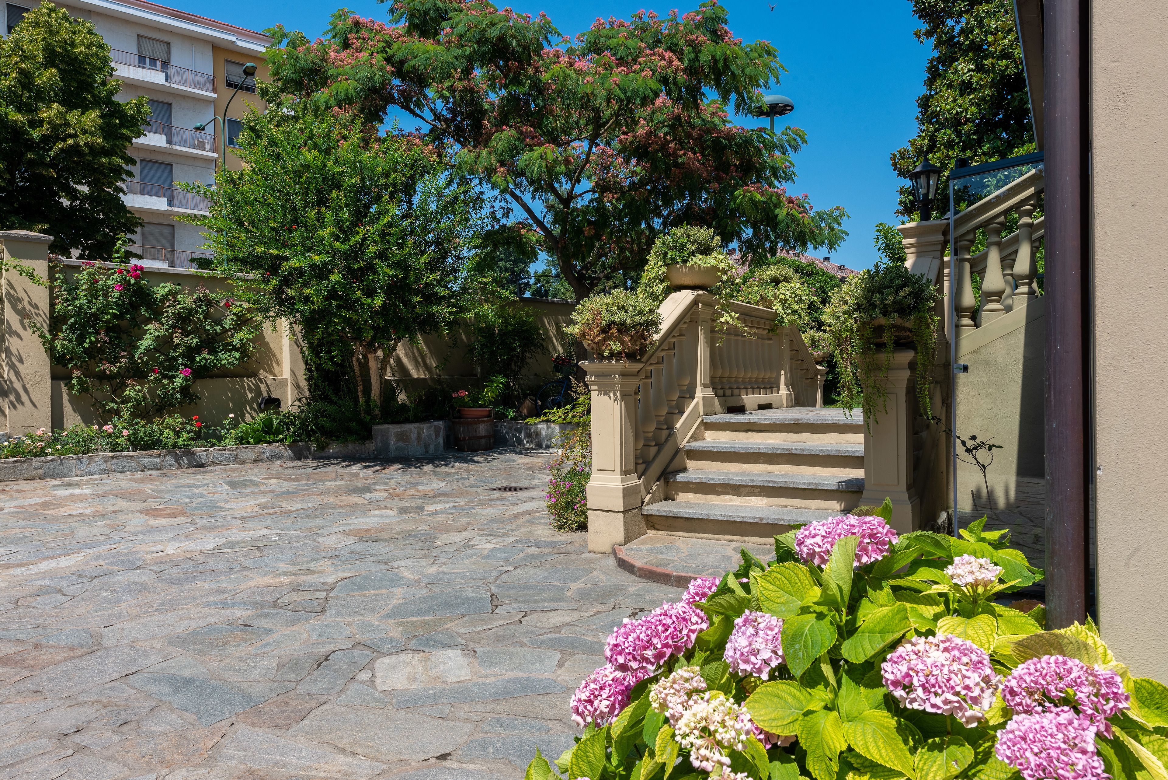 A courtyard with stone flooring, a staircase, and lush greenery.