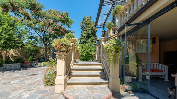 A stone staircase leading to a building with a glass entrance, surrounded by greenery and a clear blue sky. - Villa Mery (Casale Monferrato)