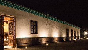 A building with a white exterior and green trim, featuring a large wooden door and a window with bars. - Refugio de Santiago Ecolodge (Lunahuana)