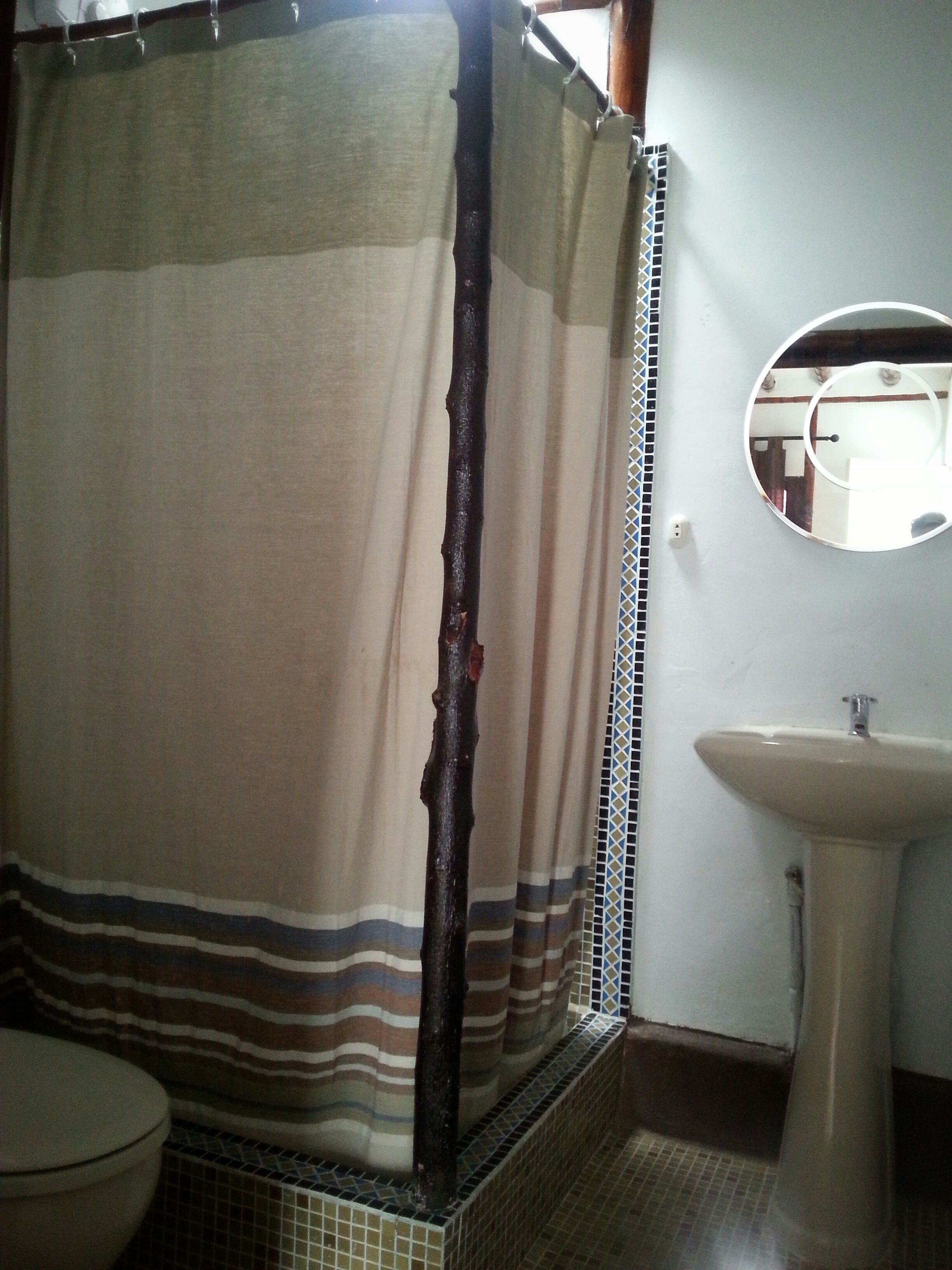 A bathroom with a striped shower curtain, a sink, and a mirror.