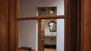 A narrow hallway leading to a room with a bed, a dresser, and a mirror. - Refugio de Santiago Ecolodge (Lunahuana)