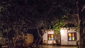 A small, single-story building with a porch and two chairs, surrounded by trees and a hammock. - Refugio de Santiago Ecolodge (Lunahuana)