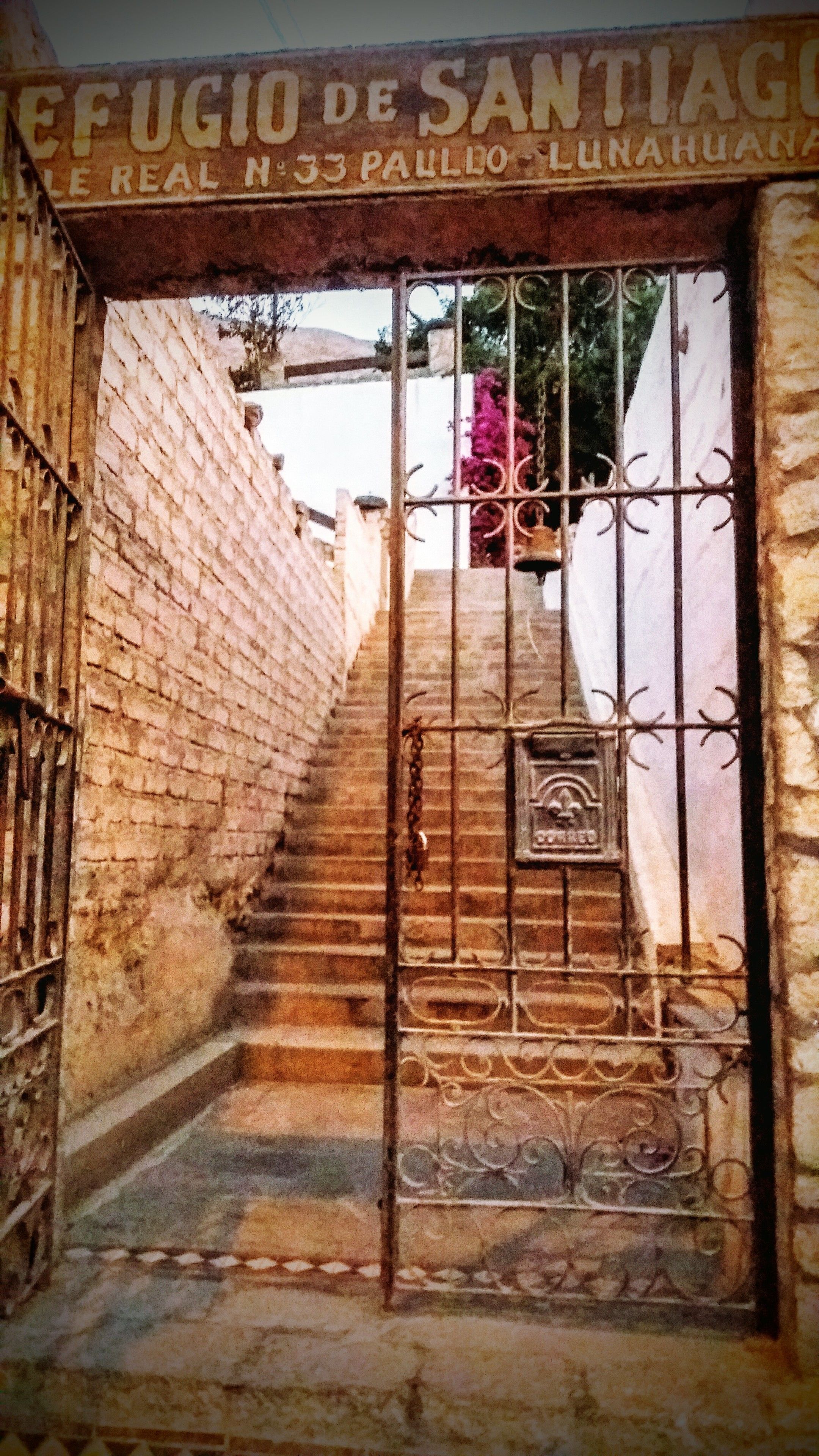 Una reja metálica con un letrero encima, que da a una escalera.
