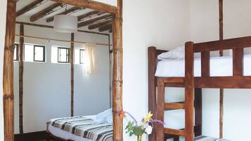 Een rustieke kamer met een houten stapelbed, een klein nachtkastje met een vaas, en een houten vloer.