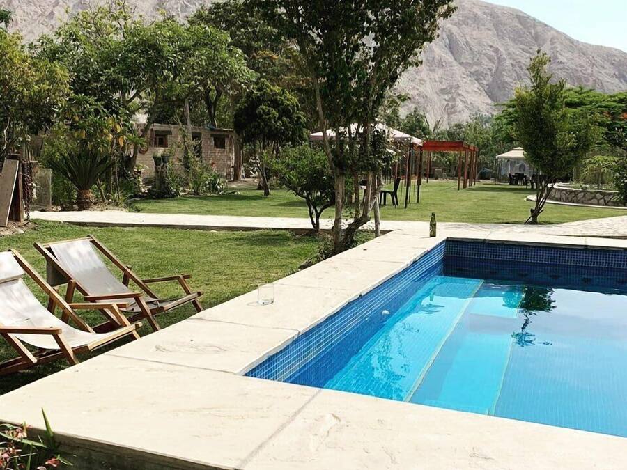 Une piscine avec des chaises longues, une pergola et une vue imprenable sur les montagnes.