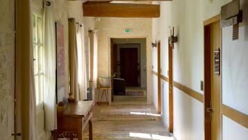 A hallway with wooden beams, a patterned carpet, and a door with a sign.