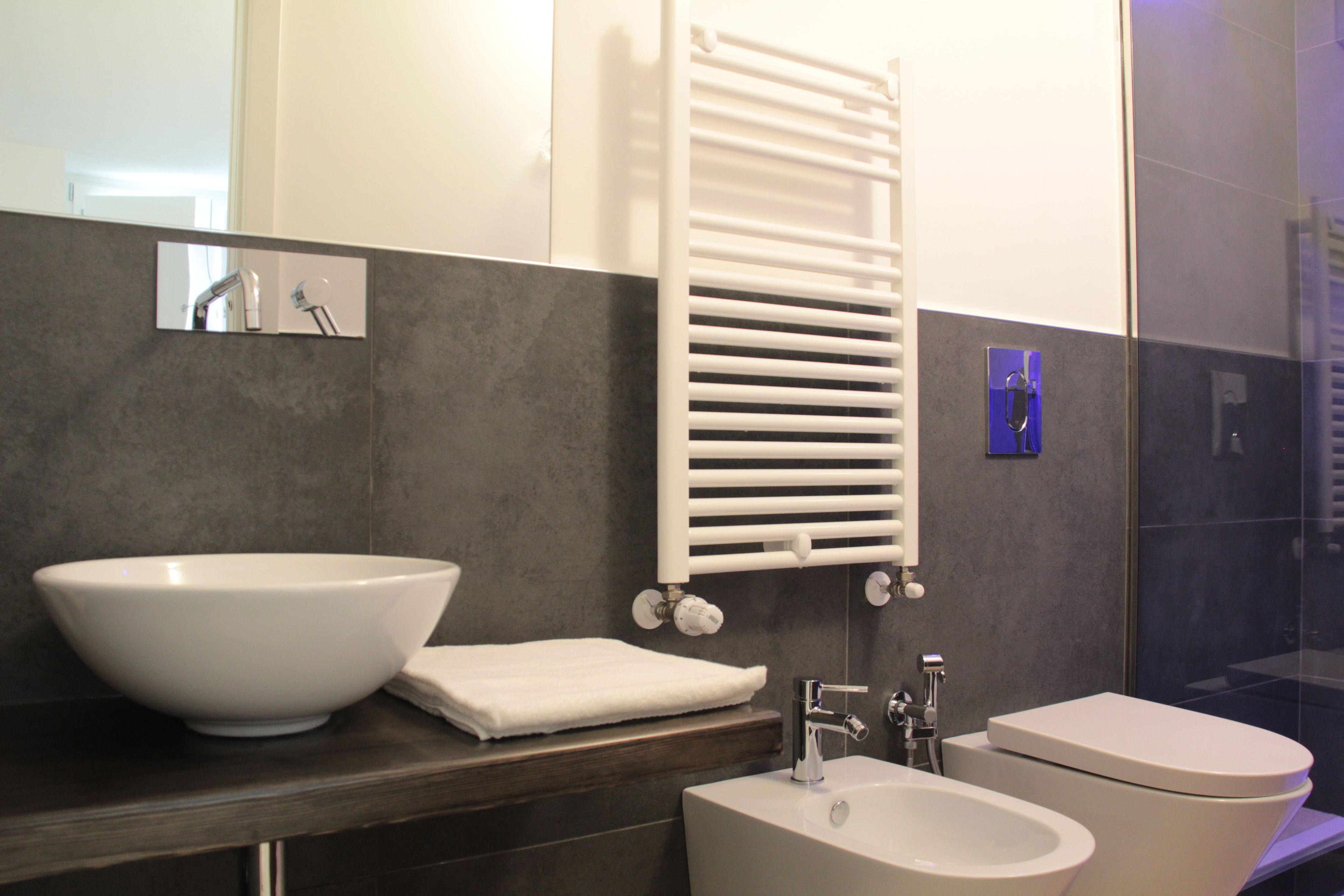 A modern bathroom with a large white sink, a white toilet, and a towel rack.