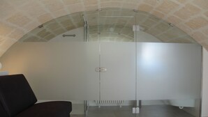 Un bagno moderno con cabina doccia in vetro, un divano di colore scuro e una parete in pietra.