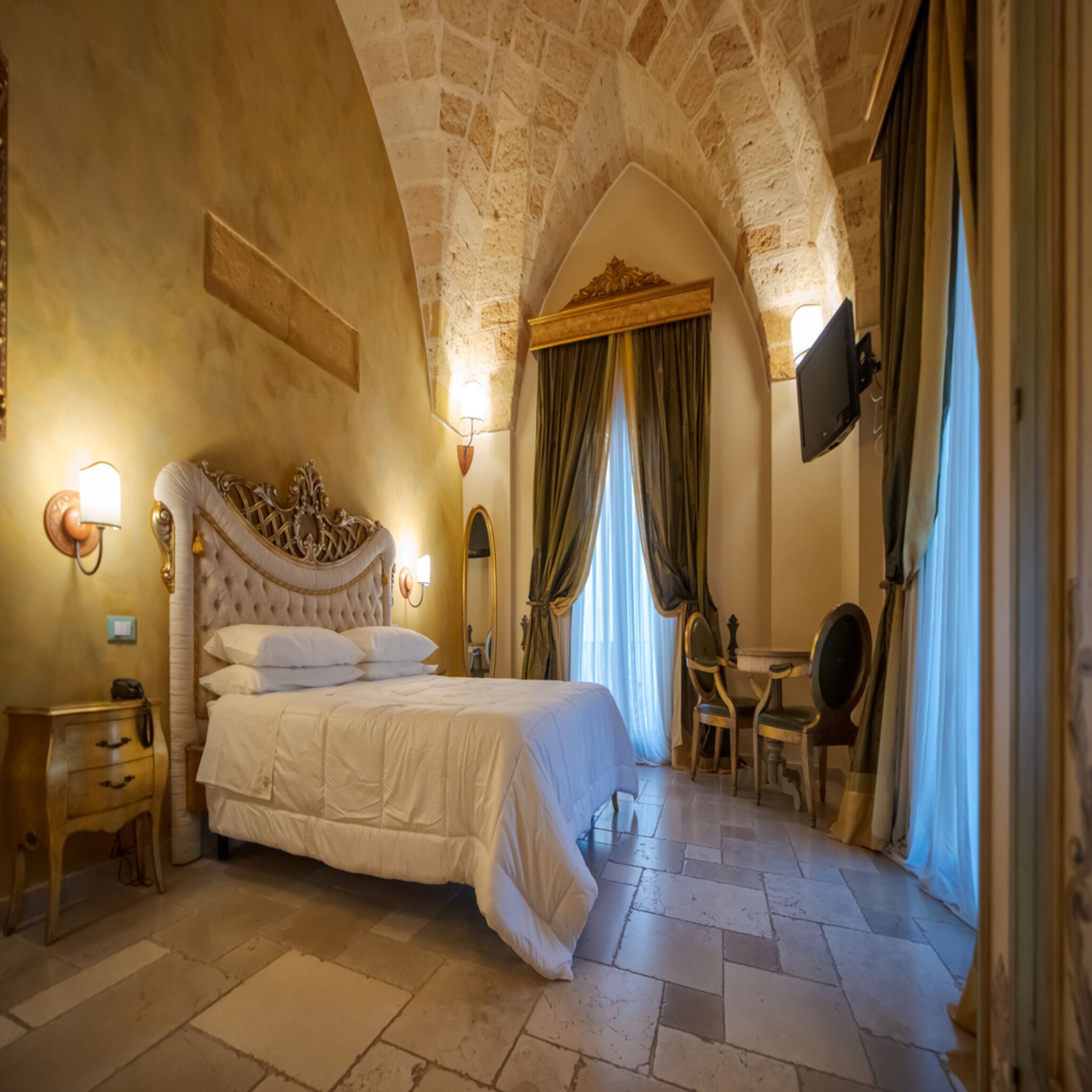 Une chambre à coucher avec un grand lit, un bureau, une chaise, une télévision et un miroir.