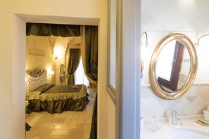 Une chambre à coucher avec un lit, un grand miroir et une salle de bain équipée d’un lavabo et d’un miroir.