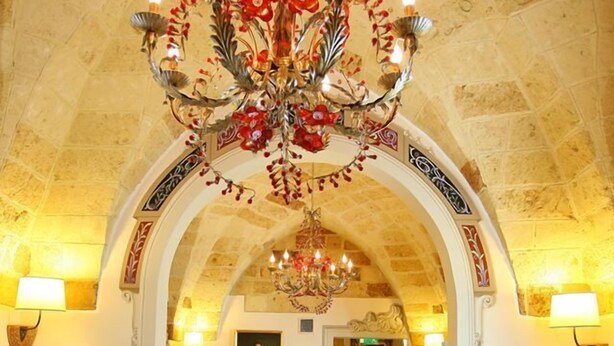 A lobby with a chandelier, arched ceiling, and a reception desk.