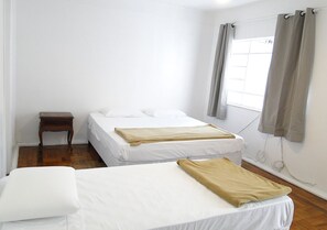 Una habitación con dos camas, una mesita de noche de madera y una ventana con cortinas.