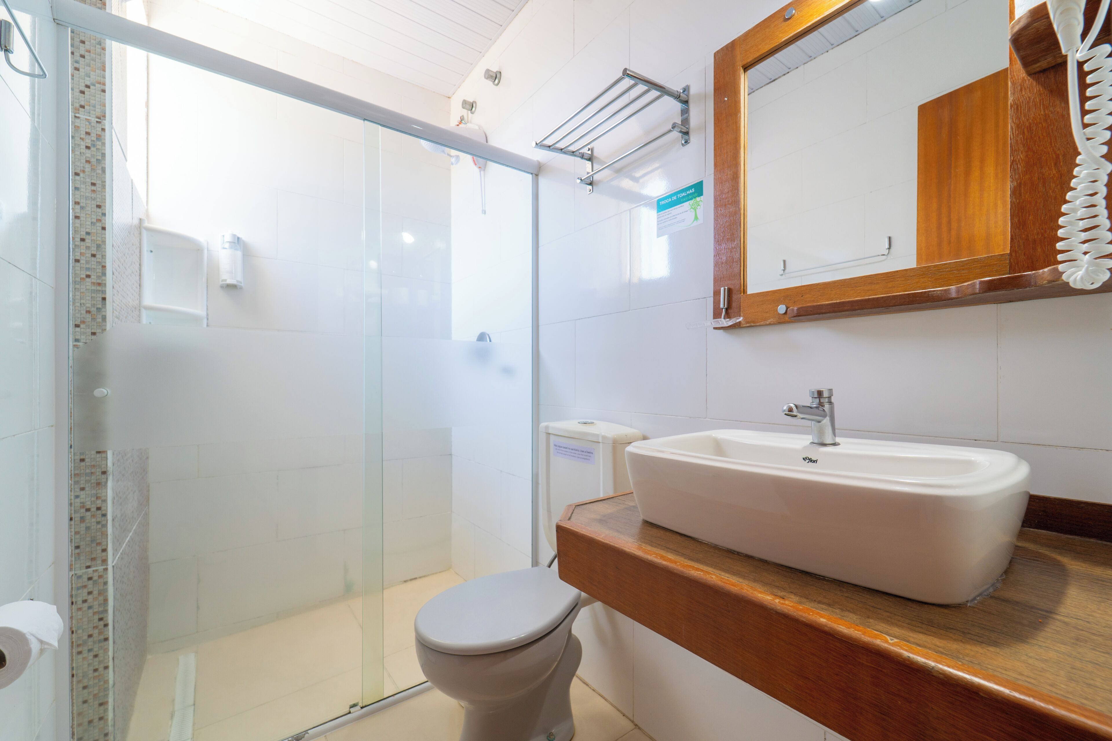 Un baño con cabina de ducha de vidrio, inodoro y lavamanos con encimera de madera.