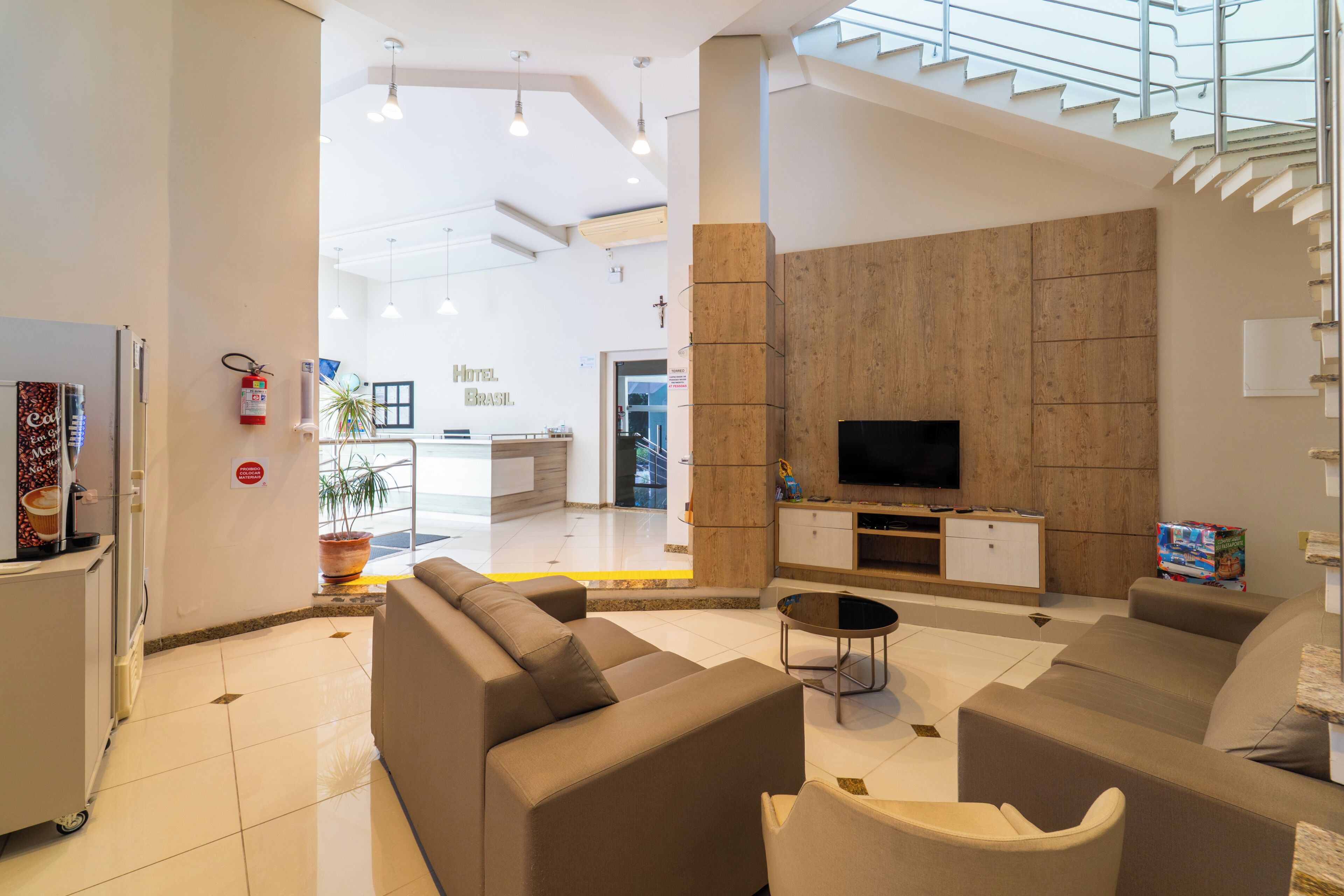 Eine moderne Hotelhalle mit einer großen Sofagruppe, einem Flachbildfernseher und einer Treppe, die zu einer oberen Ebene führt.