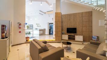 Eine moderne Hotelhalle mit einer großen Sofagruppe, einem Flachbildfernseher und einer Treppe, die zu einer oberen Ebene führt.