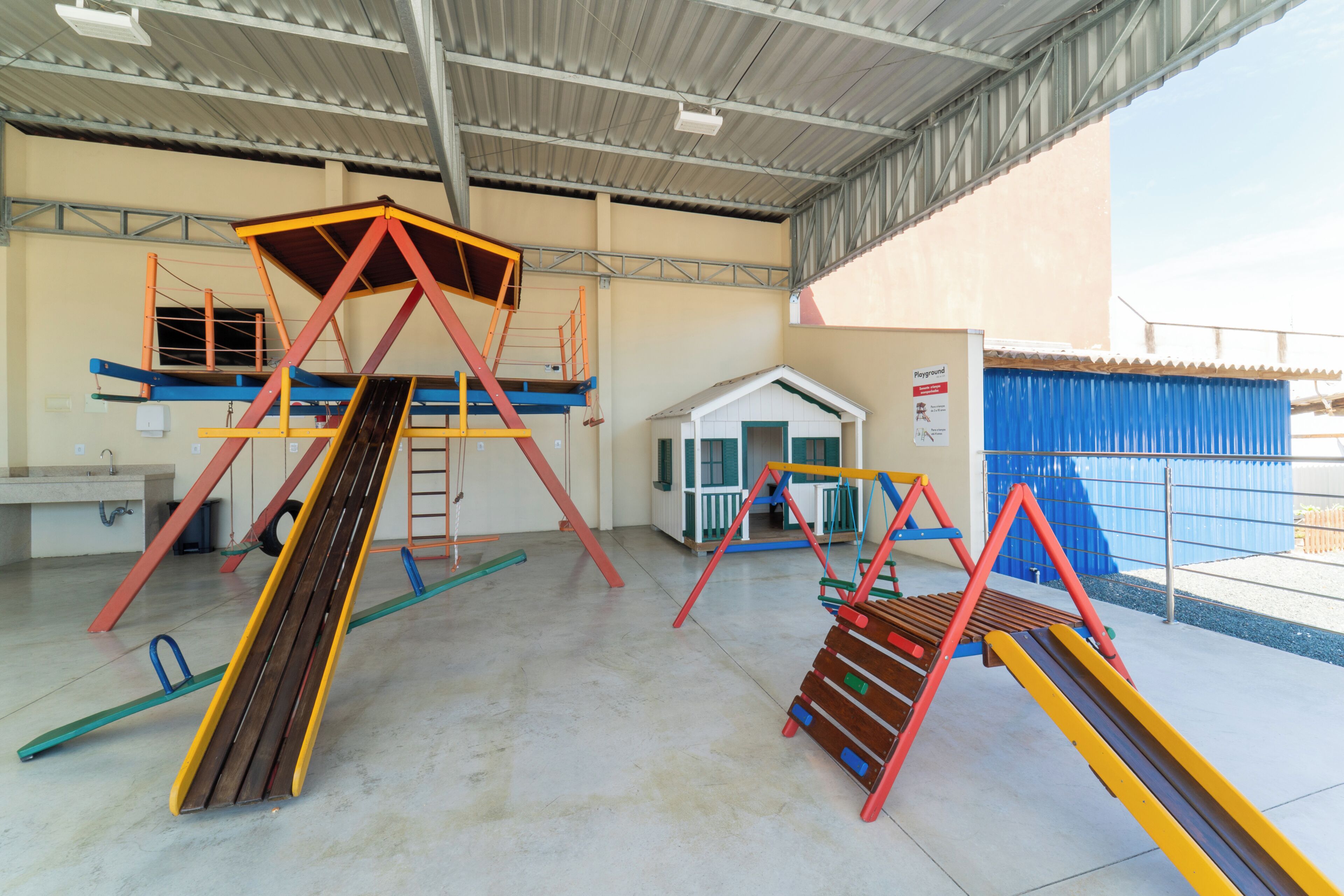 Un área de juegos interior con diversas estructuras recreativas, incluyendo toboganes y juegos de escalar.