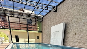 A swimming pool with a glass ceiling and a waterfall feature. - Hotel Brasil (Penha)