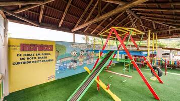 Children can play on colorful slides and climbing frames under a shaded roof.