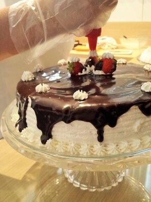 A cake with chocolate glaze and strawberries on a glass cake stand. - Hotel Brasil (Penha)