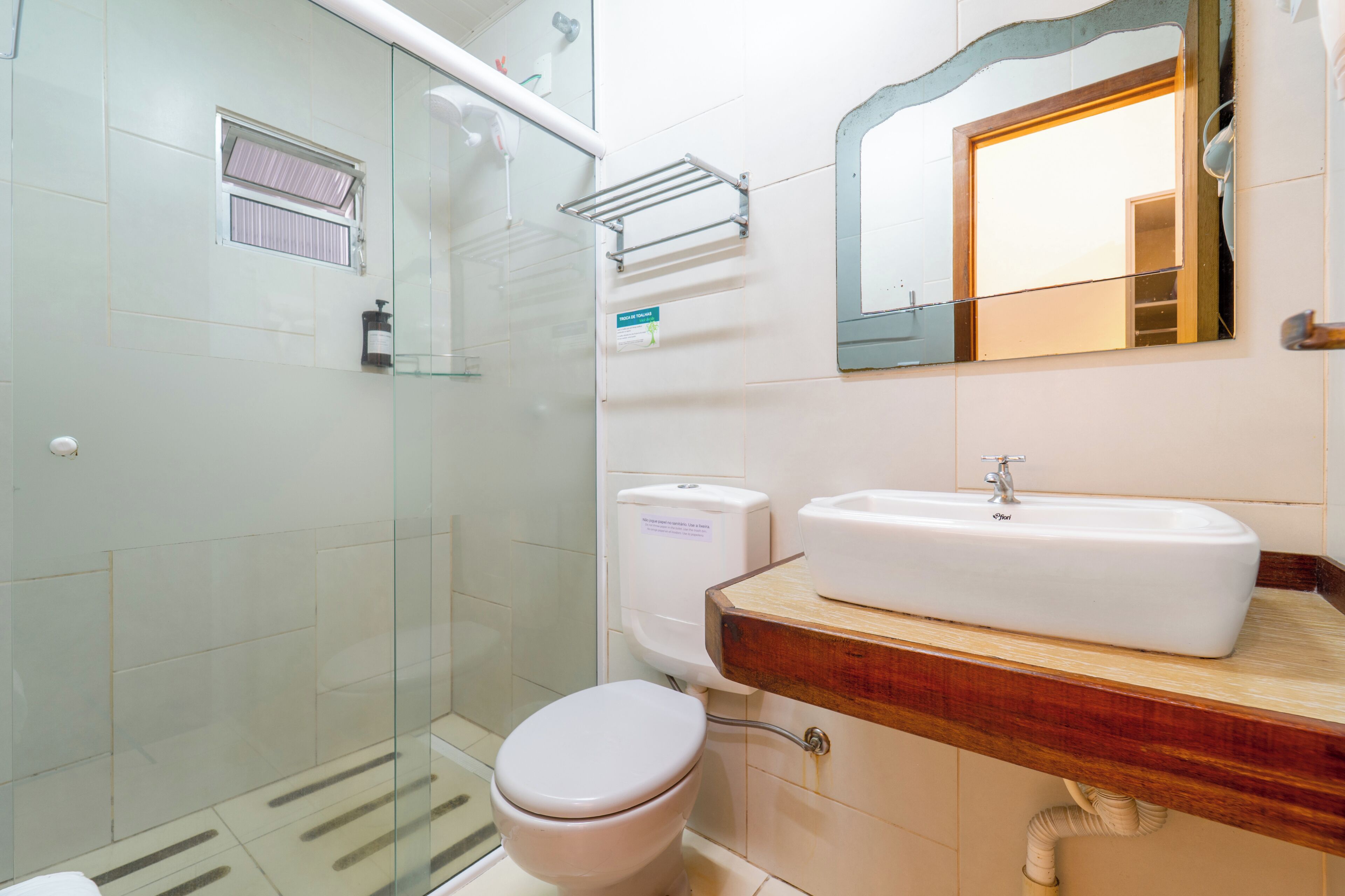 Un baño con cabina de ducha de vidrio, inodoro y lavamanos con encimera de madera.