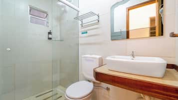 Un baño con cabina de ducha de vidrio, inodoro y lavamanos con encimera de madera.