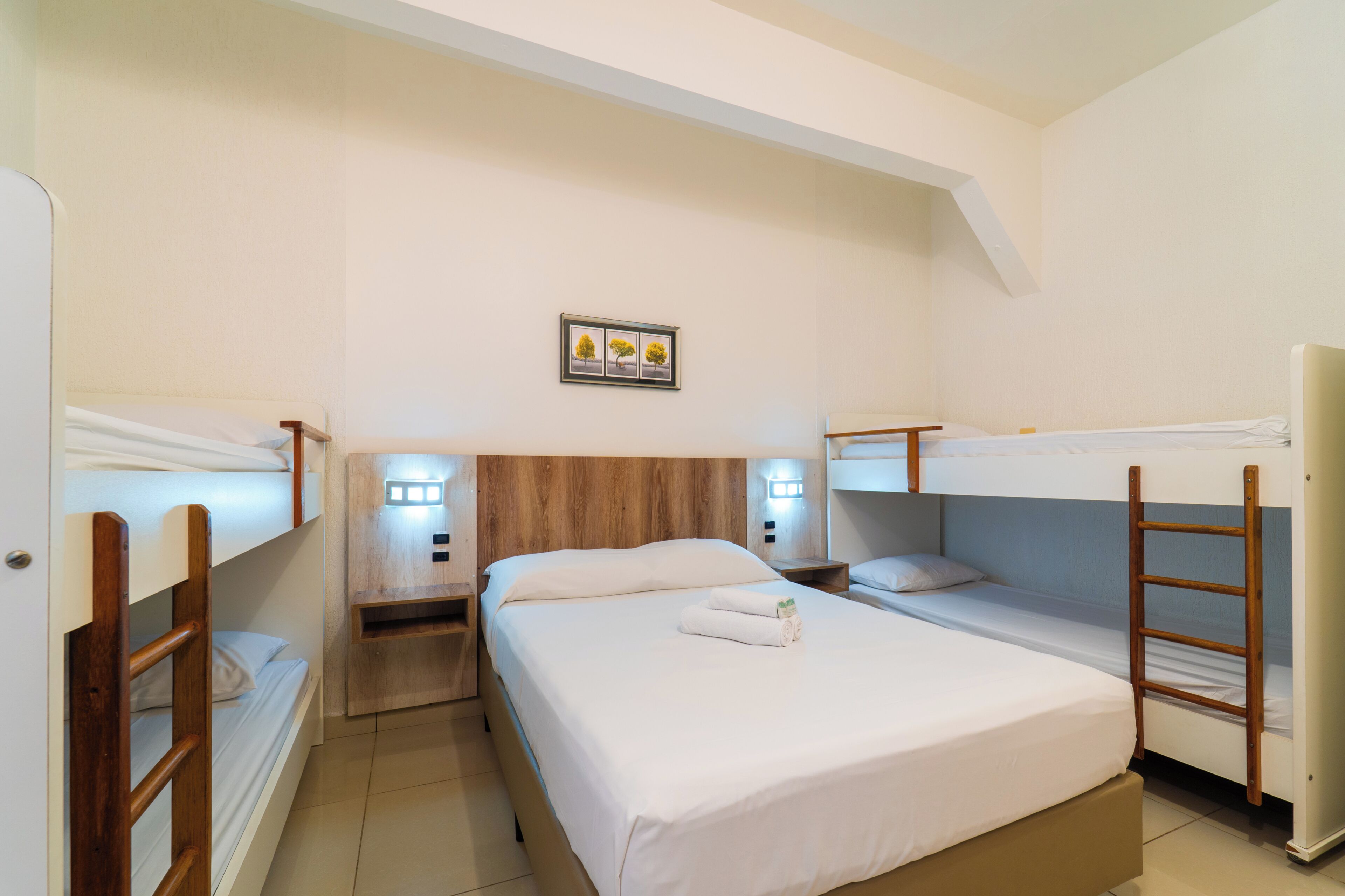 Una stanza con letti a castello, un comodino con una lampada e un quadro appeso al muro.