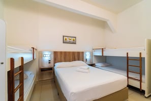 A room with bunk beds, a bedside table with a lamp, and a framed picture on the wall. - Hotel Brasil (Penha)