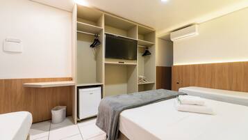 Habitación de hotel con cama, mesita de noche, armario con espacio para colgar y un cubo de basura.