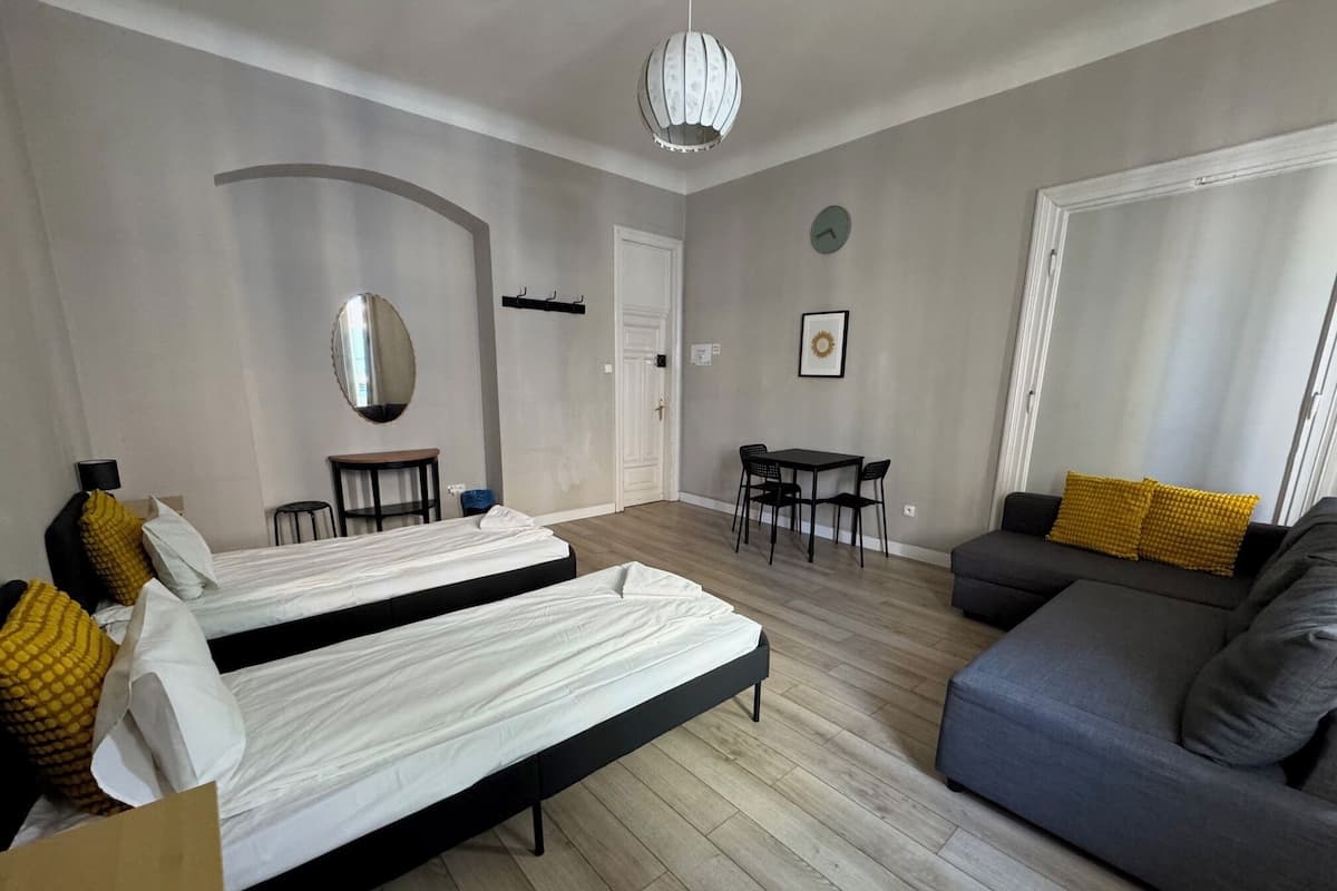 Une pièce moderne et bien éclairée, comprenant deux lits, un canapé, une table à manger et un miroir.