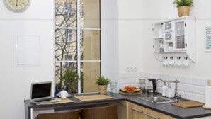 Cocina moderna con una computadora portátil sobre la encimera, un lavamanos y un ventanal con vistas a edificios.